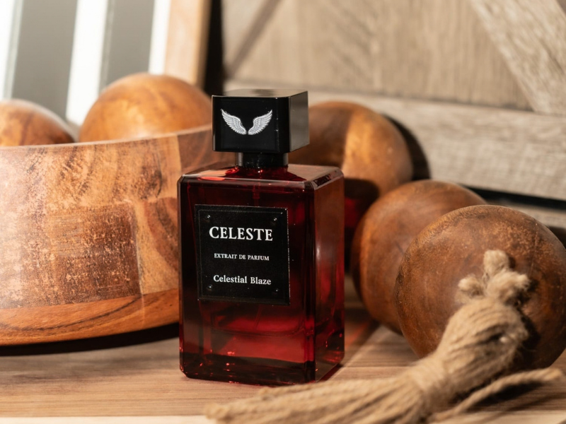 Celestial Blaze extrait de parfum bottle on a wooden table beside a wooden bowl, wooden spheres and a rope tassel